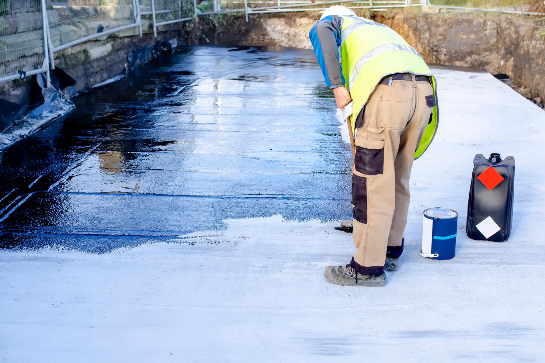 worker applying waterproofing coating.