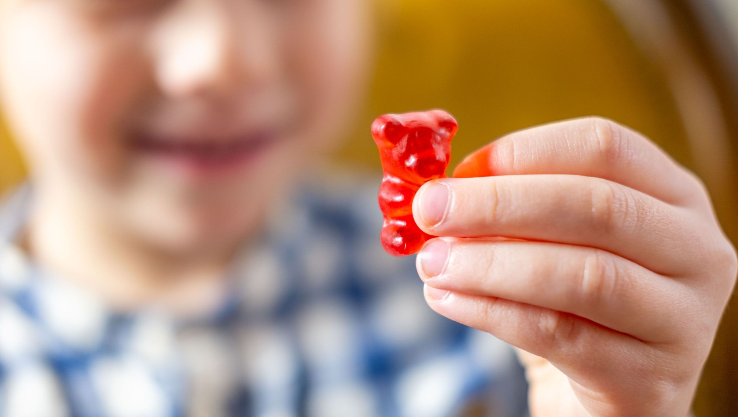 Child holding a handful of colorful gummy supplements.