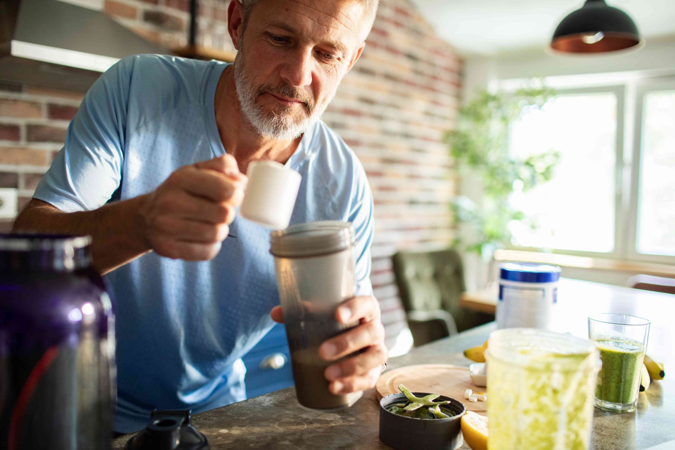 Mature man preparing a protein shake at home.