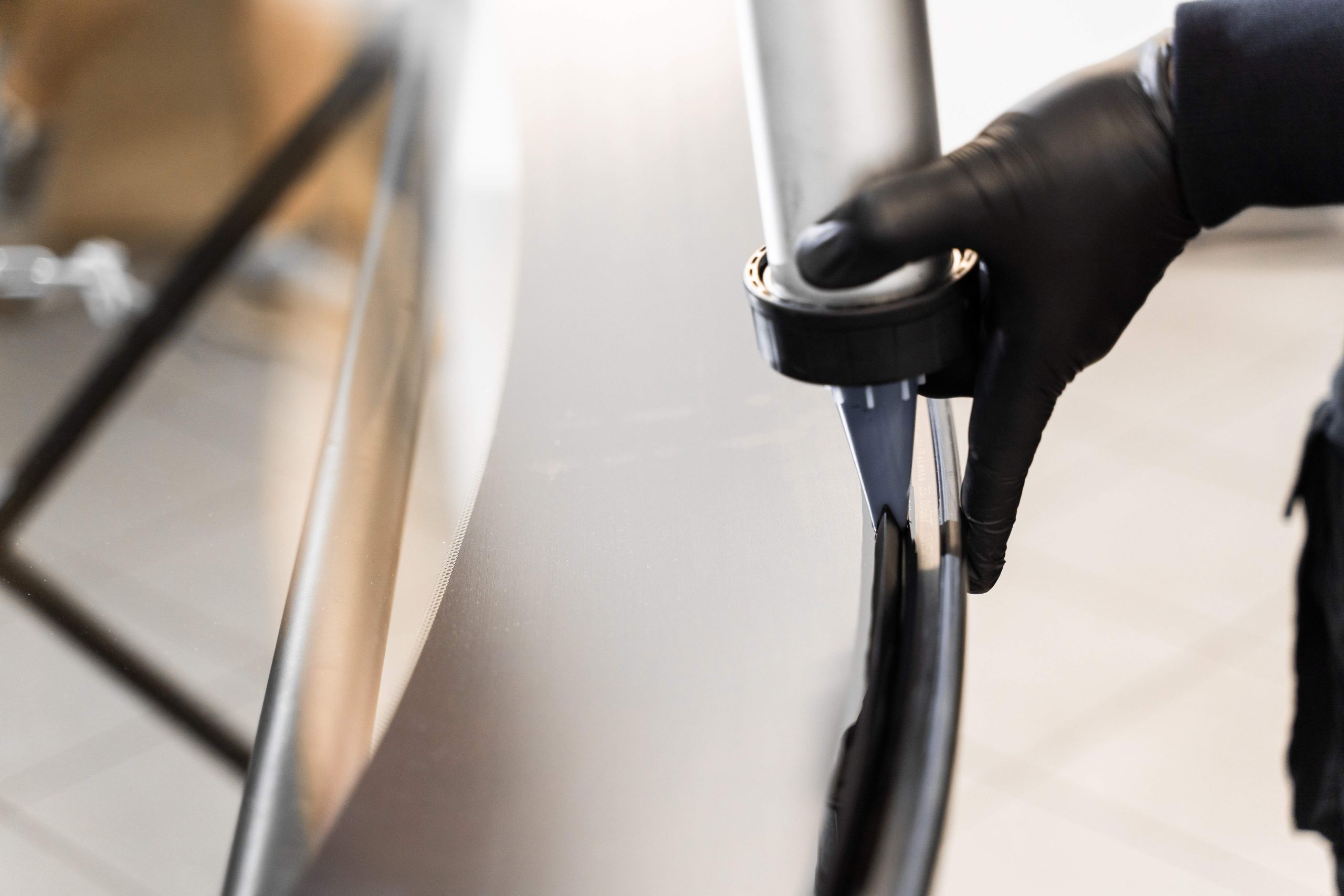 Urethane caulking gun applies flexible adhesive, forming a watertight seal at car windshield replacement. Applying adhesive to a car windshield using a caulking gun