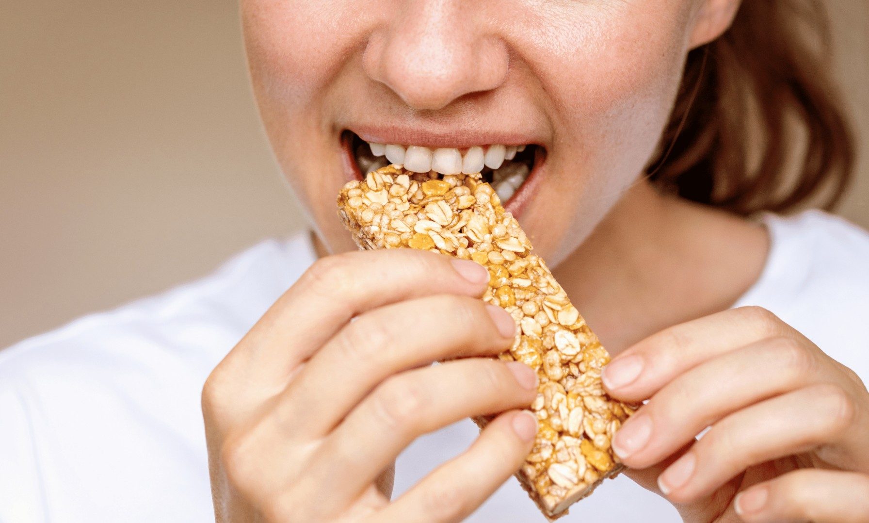 woman biting into a sports bar