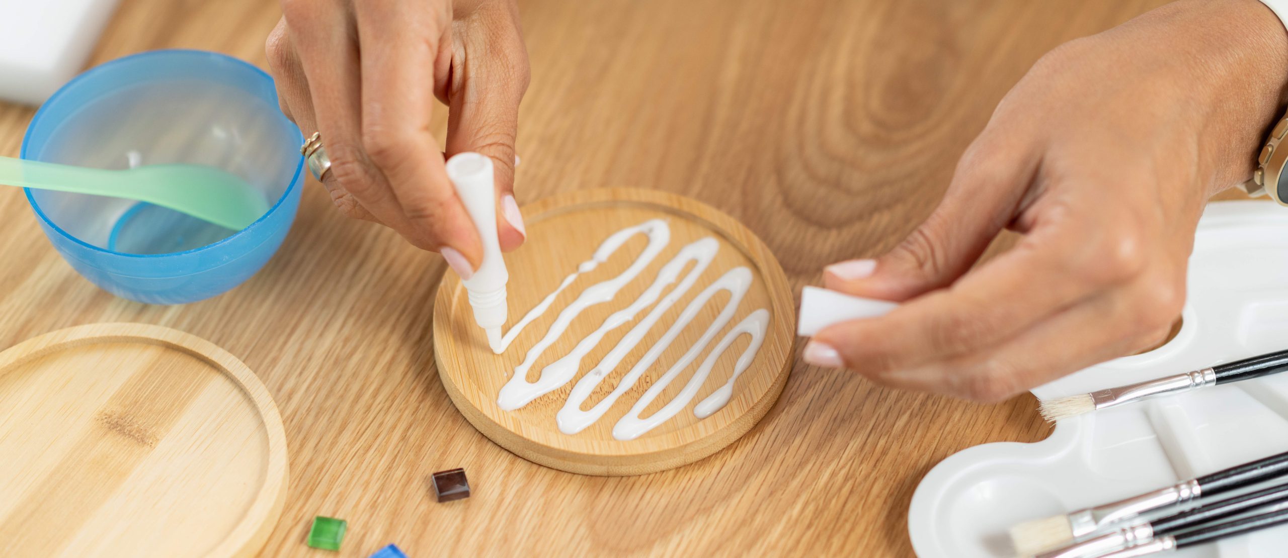 Female hands adding glue while designing decorative coasters. Highlights coordination, slow craft rhythm, and structured artistic technique.
