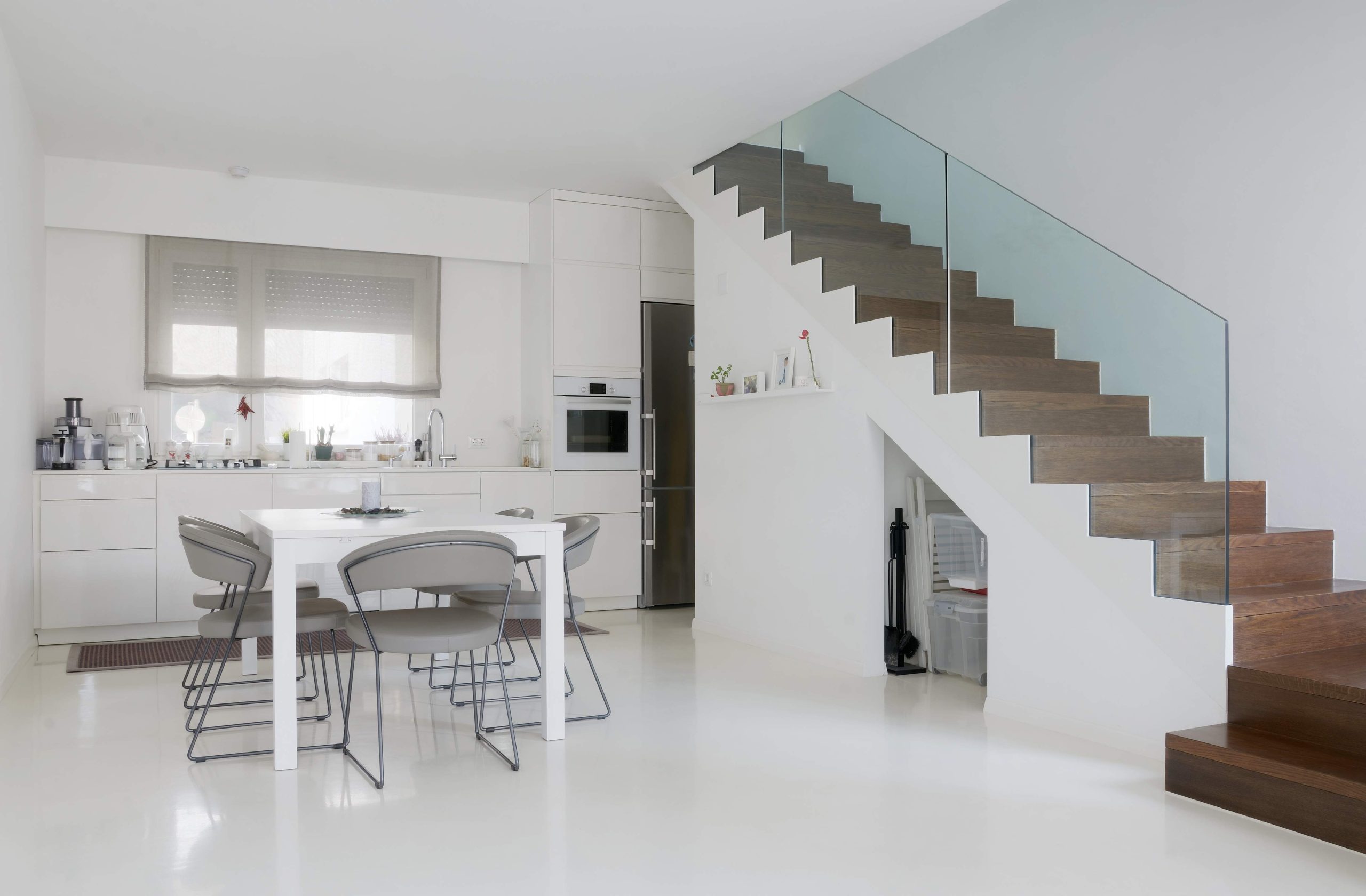 white kitchen and dining room with white epoxy floor and wooden stairs